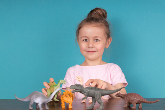Cute little girl having fun playing with a toy dinosaurs
