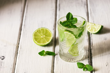 Traditional mojito cocktail. Summer cooling and refreshing drink with lime and mint on a white wooden table. Selective focus, copy space.