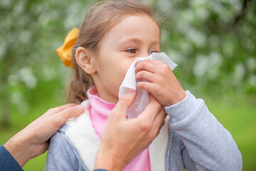 man blowing the nose of her little daughter