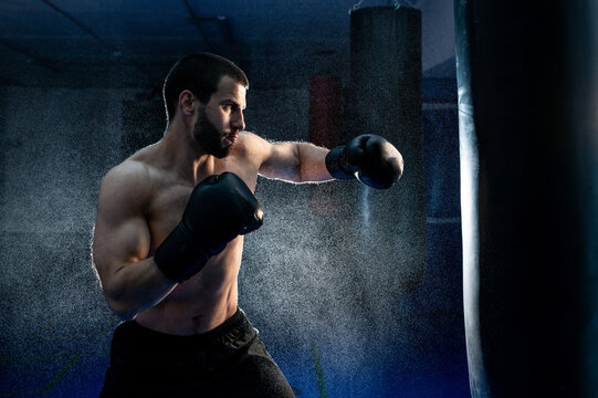 Powerful male boxer with punching bag for uppercut training