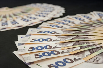 A lot of Ukrainian hryvnias, face value 500 hryvnias on a black background, nicely laid out money on black.