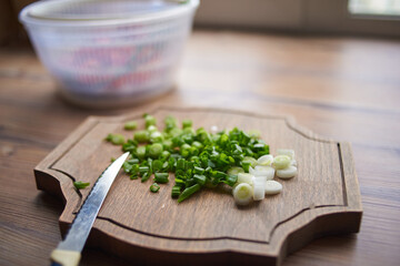 a man in his home kitchen cuts onions on a wooden Board