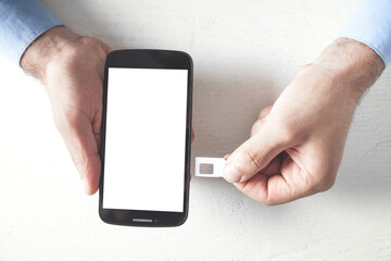Man holding Sim Card with smartphone.