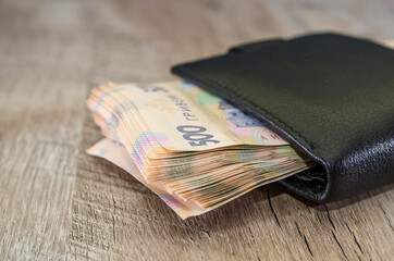 500 hryvnia in a black men's wallet on a wooden background. Close-up. A lot of hryvnia.