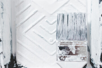 DIY and home improvement, close-up of paint tray with white glossy paint and paint brush on it