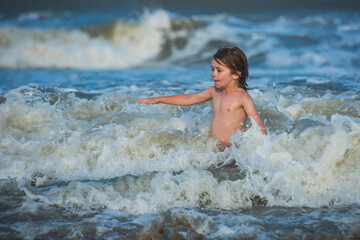 Kid playing on the beach on summer holidays. Kids jumping near the waves. Vacations on tropical island.