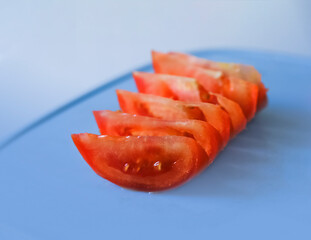 Tomato slices on cutting board. Blue background. Tomato slice concept.Sale,cooking