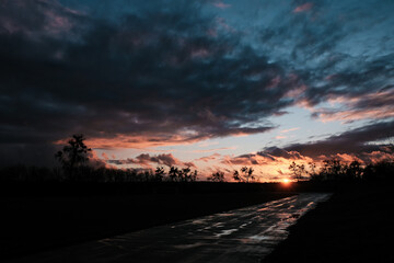 Sunset clouds after the rain over field with puddles