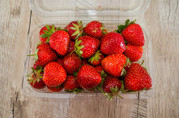 tasty strawberries in a tray on a wooden background.