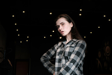 Beautiful brunette model girl posing at the dark background of interior cafe