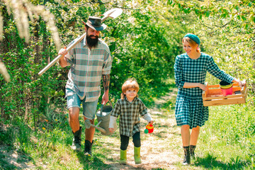 Father mother and little kid boys having fun on farm in spring. Farming gardening and family concept. Eco living for Family. Happy family in garden.