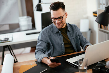 Young businessman using laptop in his office.  Handsome man working in office.	