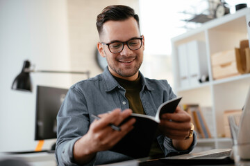 Young businessman using laptop in his office.  Handsome man working in office.	