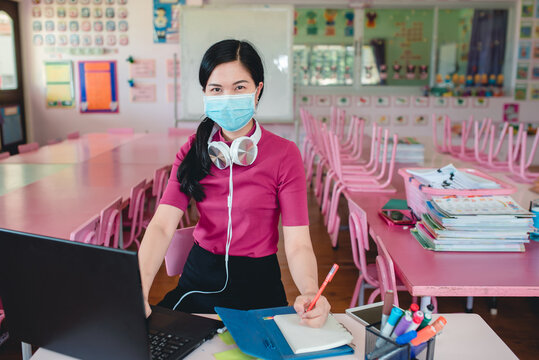 Asian Female Teacher Wearing Mask, Doctor Is Teaching Kindergarten Students Online Teachers And Students Watch Lessons On A Computer Screen Using Online Video Conferencing Systems To Teach Students.