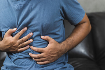 A man with a stomachache He squeezed his stomach with both hands.