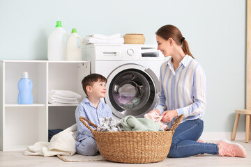 Young woman with her little son doing laundry at home