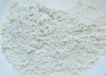 Wheat flour in a plate on green background . The flour is green background on the white plate .