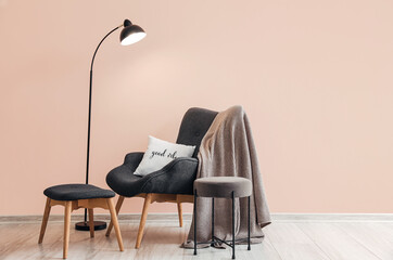 Cozy armchair with lamp near color wall in room