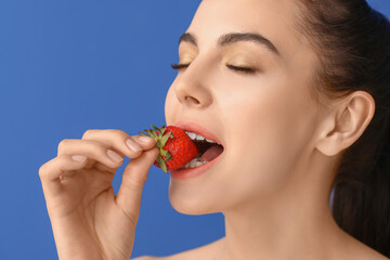 Sexy young woman with strawberry on color background