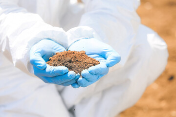 Scientist with sample of soil in field, closeup