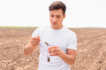 Agronomist studying sample of soil in field