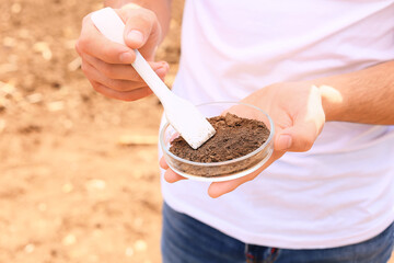 Agronomist studying sample of soil in field, closeup