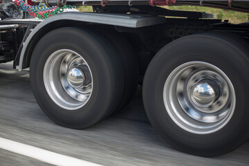 Shiny chrome aluminium wheel caps of a 18 wheeler in motion. Freight cargo truck wheels close up on the road spinning in speed motion blur