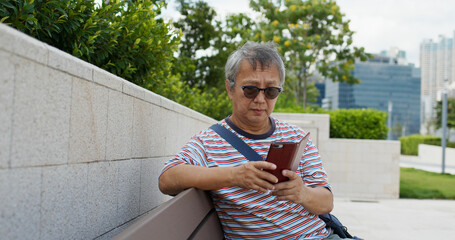 Obraz premium Asian old man use of mobile phone in city