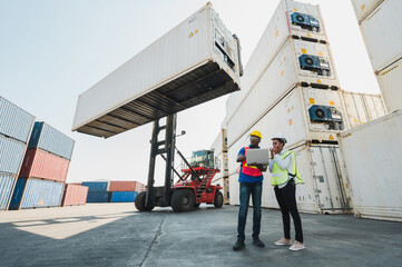 Two Black foreman man & woman worker working checking at Container cargo harbor holding laptop to...