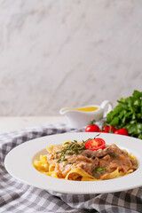 Plate with tasty beef stroganoff and pasta on table