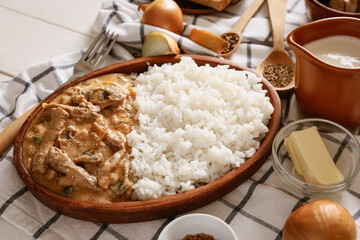 Plate with tasty beef stroganoff and rice on table