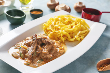 Plate with tasty beef stroganoff and pasta, closeup
