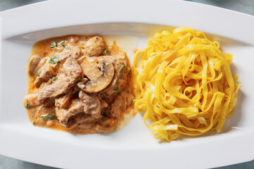 Plate with tasty beef stroganoff and pasta, closeup