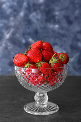 Glass dessert bowl with ripe strawberry on table