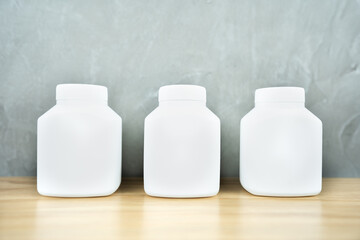 Medicine pharmacy bottle for tablet drug with empty label on wooden table.Blank white plastic cosmetic product template.