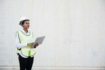 Black foreman woman worker working checking at Container cargo harbor holding laptop computer to loading containers. African dock female staff business Logistics import export shipping concept.