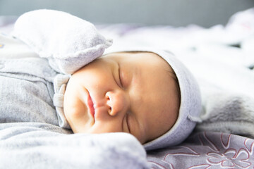 Beautiful newborn sweetly sleeps in the crib and has beautiful dreams