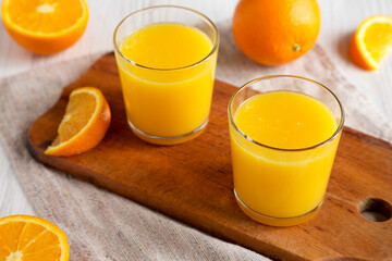 Healthy Orange Juice on a rustic board on a white wooden background, low angle view.