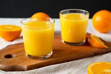 Fototapeta na wymiar Healthy Orange Juice on a rustic board, side view. Close-up.