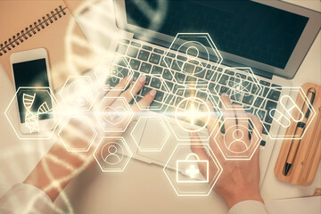 Double exposure of woman hands working on computer and DNA hologram drawing. Top View. Medical education concept.