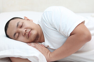 Good quality sleep concept, Asian man sleeping on bed with fresh happy face, good rest after hard day of working