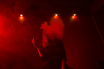 Girl model smokes vape in red light.
