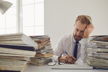 Exhausted tired worker at the workplace covered his face with his hands in the office