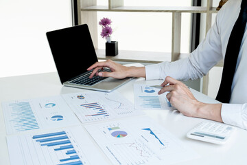 business man is sitting at a desk and use laptop calculating financial graph that show results In the office