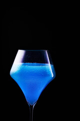 Blue drink is poured into a glass. Black background.