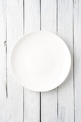 Empty white dish on wooden table. Top view