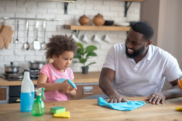 African american bearded man and his daughter doing cleaning together and feeling great
