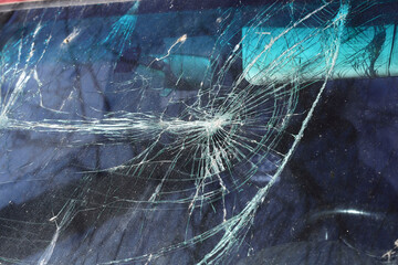 Blurred background of a broken car windshield. Closeup cracks and scratches on a windshield....