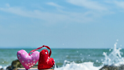 Red hearts. Soft toy. Handwork. Sea shore. Waves hit the stones.