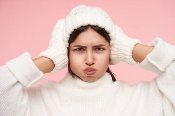 Gloomy of young green-eyed brown haired lady with natural makeup frowning eyebrows while looking...